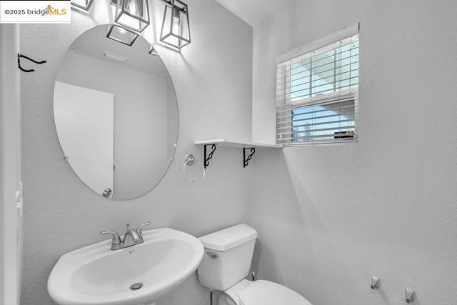 Bathroom featuring a textured wall and toilet