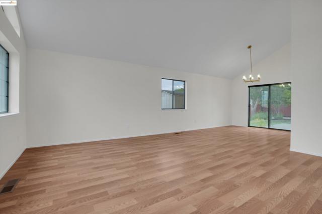 Spare room with light wood-style floors, high vaulted ceiling, and a chandelier