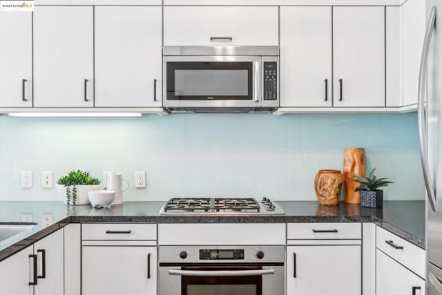 Kitchen featuring stainless steel appliances, white cabinetry, and dark countertops