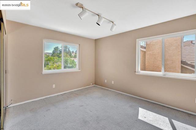Carpeted empty room featuring track lighting and baseboards