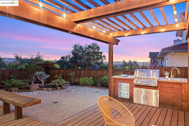 Wooden terrace with area for grilling, a fenced backyard, and a pergola