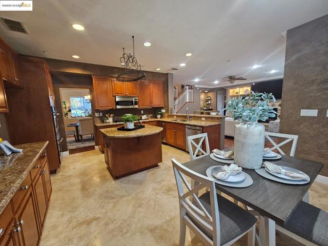 Kitchen featuring light stone countertops, brown cabinetry, a peninsula, recessed lighting, and ceiling fan