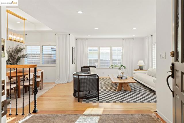 Living area with light wood-type flooring, healthy amount of natural light, recessed lighting, and a raised ceiling