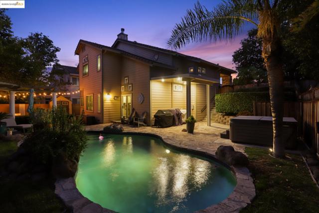Back of house featuring a hot tub, a fenced backyard, a chimney, and a patio area