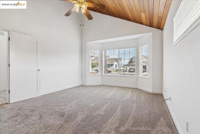 Carpeted empty room featuring wooden ceiling, a ceiling fan, and high vaulted ceiling