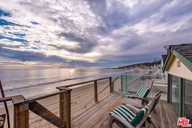 Searching for your own slice of paradise in a highly sought-after Malibu Colony location? This remarkable 4-bedroom, 4-bath home has had the same owner since 1960, and now you have a rare opportunity to make it your own. Its multiple decks and patios offer panoramic ocean views and spectacular sunsets. Vaulted ceilings with exposed beams soar overhead in the living room as abundant natural light gleams on the hardwood-style flooring and grand fireplace. An elegant archway leads to the dining room, and you'll have a seamless flow into the sun-drenched family room, creating a bright and open interior that's ideal for entertaining. Your galley kitchen welcomes the avid chef with a built-in refrigerator/freezer, stainless steel appliances, and recessed lighting. Gather around the wood-stove as you enjoy game nights in the upstairs den before retiring to the comfort of your main bedroom, featuring a beautifully tiled, glass-enclosed rainfall shower and a private balcony overlooking the beach where you can watch brilliant sunsets. Neutral color tones and sunlit windows help you to wake up refreshed in the well-sized private accommodations. There's an office on the top floor that can be converted into a gym/yoga room to work up a sweat while enjoying incredible ocean views. Nothing says "relax" like lounging on the large brick patio surrounded by fresh salt air. A covered area offers an ideal spot for outdoor dining, and a raised deck has steps leading to the sandy beach. Grab your chance to indulge in the beachfront lifestyle you deserve in an exclusive 24-hour guard-gated community. Come take a tour while you still can!