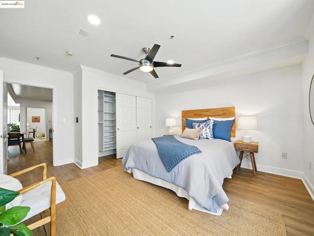 Bedroom with wood finished floors, crown molding, a closet, and a ceiling fan