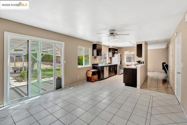 Kitchen with healthy amount of natural light, light tile patterned flooring, light countertops, and a ceiling fan