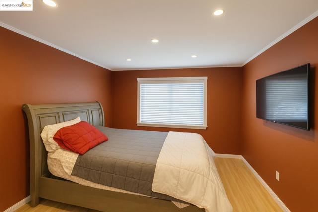 Bedroom with ornamental molding, wood finished floors, and recessed lighting