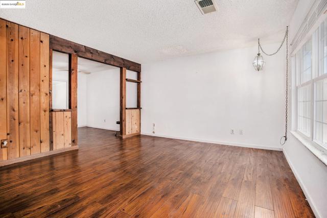 Spare room with dark wood-style floors, a textured ceiling, and wood walls
