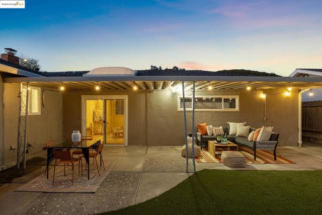 Back of house at dusk featuring a patio, stucco siding, and outdoor lounge area