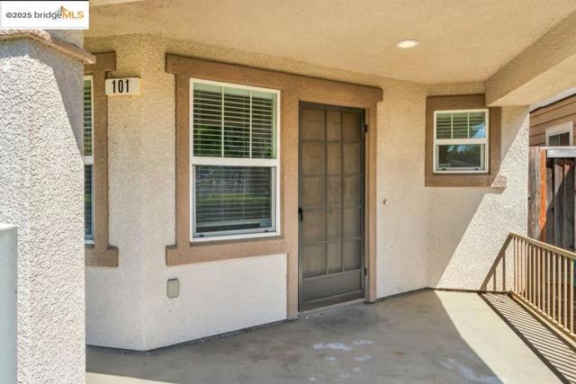 View of exterior entry with stucco siding and a patio