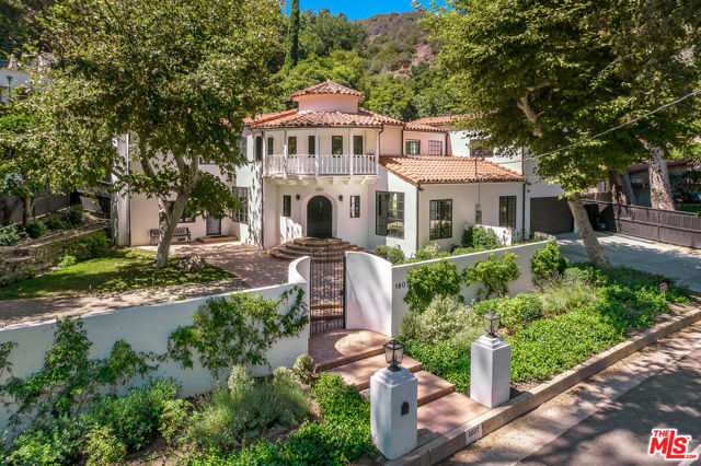 1807 Benedict Canyon Drive Beverly Hills, California This one-of-a-kind two-story Spanish-style home, originally built in 1928, has been completely redone while respecting the original architectural style and character of the bygone era. It's finished with the highest quality fixtures and amenities desired for 21st-century living. Located in beautiful Benedict Canyon, you are nestled in greenery and nature, yet just a few minutes drive from the legendary Beverly Hills Hotel. And let's not forget Warner Avenue Elementary. Entering through the arched entry door, you'll be welcomed into the two-story turret-style entryway. The original spiral staircase with twisted wrought iron detail transports you to another decade, while at the same time, the black-and-white marble and Belgium-honed limestone flooring set the tone for the sophisticated color palette of the home. Step down from the entry and into the character-filled living room. Notice the original 12-foot wood beam ceilings, original heating and air conditioning grates, and push-button on/off switches, which are featured throughout the home. The heart of the home is the kitchen, and this one is any cook's dream come true. With its top-of-the-line appliances, including a Lacanche range imported from France, you'll see that no detail or expense has been spared. The oversized marble center island with bar seating is the perfect spot to enjoy a glass of wine from the built-in wine refrigerator. Passing through double arches from the kitchen, you move into the breakfast room, with beautiful views of the front patio nestled under a canopy of sycamore branches. Beyond the kitchen and breakfast room sits the cozy family room another original room in the house with its classic wood-burning fireplace. This special room has its own private entrance; a perfect way to receive guests. The primary bedroom is full of opulent appointments - from the spacious walk-in dressing room to the gray-on-gray marble bathroom featuring a large soaking tub and double sized shower. The additional three bedrooms, one which is currently being used as an office, are all upstairs along with the primary bedroom. They are nicely appointed with full baths, high ceilings, large walk-in closets and beautiful views. The yard is ideal for entertaining, with a black-bottom pool, spa, and easy access to the indoor/outdoor bathroom. The party possibilities are endless. The two-car finished garage is equipped with 220EV, and an abundance of additional parking is an added bonus for this location. Adjacent to the garage is a gym and bathroom.