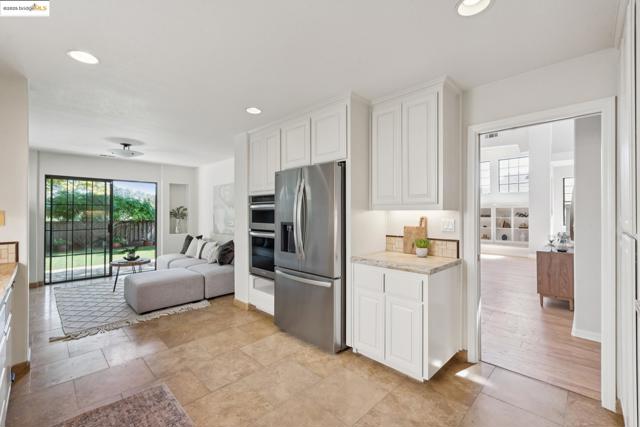 Kitchen featuring recessed lighting, appliances with stainless steel finishes, white cabinets, open floor plan, and light stone counters