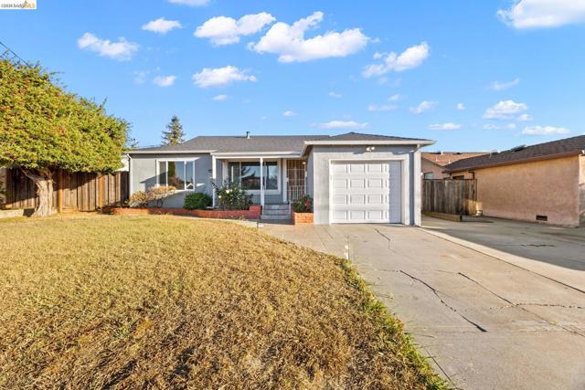 Single-story residence featuring a gray exterior, attached garage with a white panel door, and a front yard with a mature tree