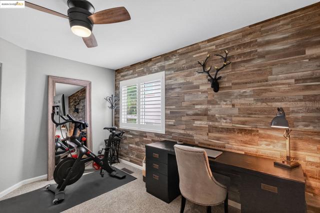 Bedroom featuring carpet flooring, a ceiling fan, and wooden walls