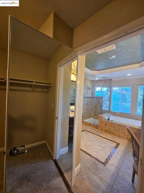 Bathroom featuring a walk in closet, a shower stall, a garden tub, tile patterned flooring, and a textured ceiling