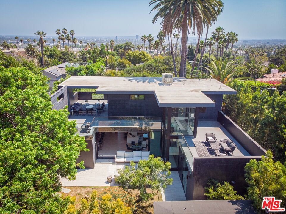Nestled just moments from Runyon Canyon and the iconic Sunset Strip, this extraordinary modern estate embodies the essence of architectural innovation and serene luxury. Inspired by Italian modernism and Japanese design principles, this 3,100 sq. ft. masterpiece is a testament to bespoke craftsmanship and meticulous attention to detail. Set on a sprawling 9,000+ sq. ft. lot, this newer construction residence boasts 4 distinctive bedrooms and 3 baths, offering unparalleled versatility and sophistication. Beyond the private gate, discover a tranquil eco-friendly oasis with drought-resistant landscaping that sets the stage for unparalleled relaxation. Upon entry, a grand gallery-style foyer welcomes you with 21-foot-tall 3D perforated brass facade and high-end fixtures, complemented by unique marble and white oak wood floors. The heart of the home is a luminous great room featuring a Bio Flame fireplace, seamlessly flowing into a dining area and a state-of-the-art kitchen adorned with edgy quartz countertops, La Cornue range, and SubZero appliances. The outdoor space is a true retreat, highlighted by a salt-water pool, geometric green statement wall, expansive deck, and multiple lounging areas amidst lush greenerya perfect setting for entertaining or peaceful solitude. Upstairs, the master suite offers a sanctuary of its own, complete with glass-enclosed decks that capture sweeping views of the city skyline, mountains, and coastline. Additional amenities include a two-car garage for luxury vehicles and smart home features for added convenience. Located in proximity to historical estates once inhabited by Hollywood luminaries, this residence offers both privacy and prestige. Revel in the quintessential Hollywood lifestyle, where seamless indoor/outdoor living and breathtaking panoramas define everyday luxury. Escape the bustle yet stay connectedmoments from cultural landmarks like the Hollywood Bowl and the vibrant Sunset Strip, yet worlds away from the noise and traffic. This is more than a home; it's a rare opportunity to own a piece of architectural brilliance in one of Los Angeles' most coveted neighborhoods.