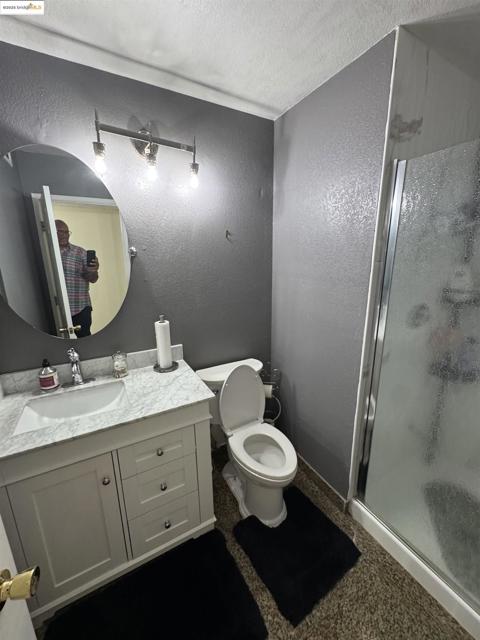 Full bath with a textured wall, vanity, a shower stall, and a textured ceiling