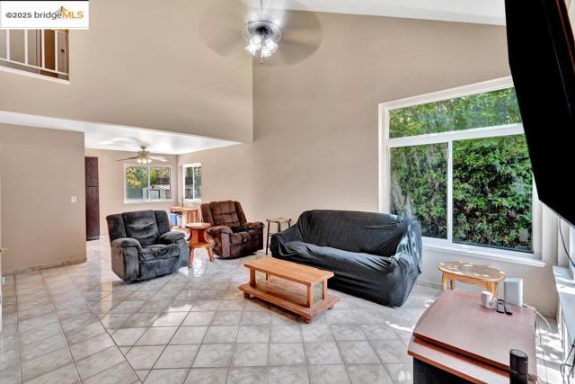 Living area featuring high vaulted ceiling, ceiling fan, and light tile patterned flooring
