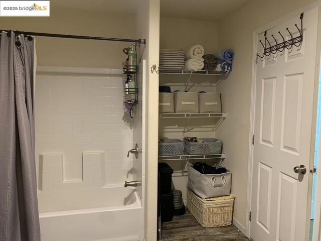 Bathroom featuring shower / tub combo with curtain and wood finished floors