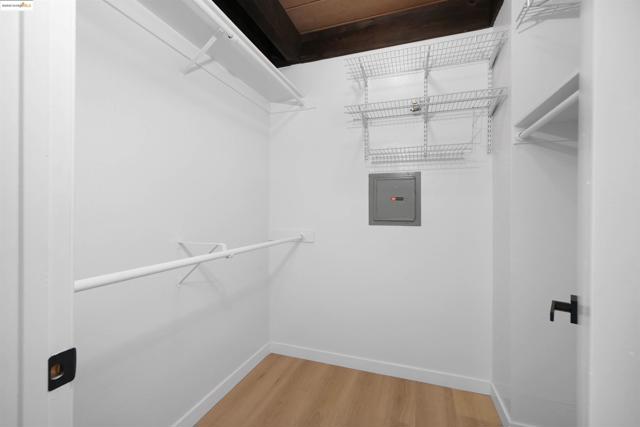 Walk in closet featuring electric panel and light wood-style floors