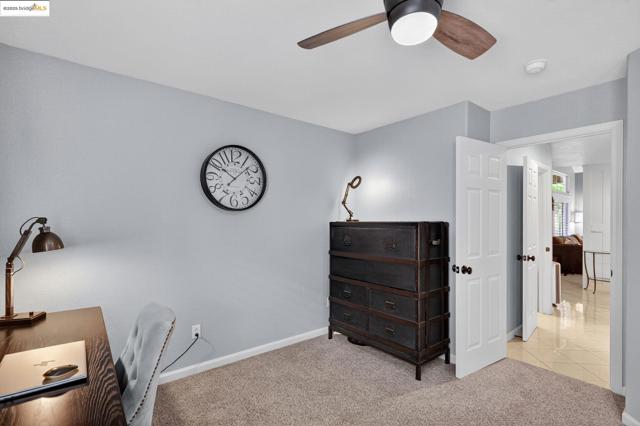 Home office featuring light colored carpet, light tile patterned flooring, and ceiling fan