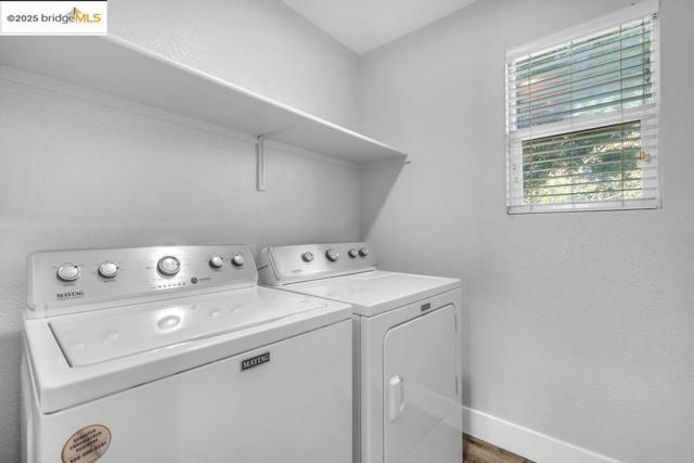 Laundry area featuring washer and clothes dryer and a textured wall
