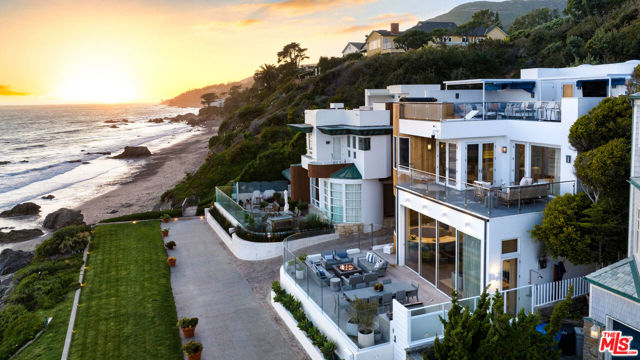 A completely remodeled and stunning three-story architectural oceanfront home in Malibu with direct beach access is located at the end of the private and gated Sea Level Drive community. No expense was spared in the amazing remodel by designer, Nathan Turner, this 4 bedroom/5.5 bath luxury home with sweeping ocean views, offers a main level sun-filled living room with fireplace, bar with dropdown TV, high ceilings, and walls of glass that open to a large entertainers patio with BBQ island and fire pit. The formal dining area that overlooks the living room is open to a gourmet kitchen with high-end appliances, a waterfall island, and state-of-the-art appliances. The 2nd level offers an impressive ocean view owner's suite with fireplace, sitting/office area, private deck, and a luxurious spa bathroom with double vanities, ocean view steam shower, large custom closet, and additional custom built-ins; plus an additional two en-suite bedrooms with private patio. A beautiful media room is located on the lower level along with a private entrance guest suite. The gorgeous ocean views continue on the large rooftop deck with a hot tub, entertainment center, and B-B-Q. Close to Trancas shops, Malibu Park schools, and Zuma Beach, can be sold furnished. With just 37 homes, private, gated Sea Level Drive is one of Malibu's most desirable addresses. Elegant contemporary design, spectacular open spaces, and non-stop ocean views work together perfectly to create an ambiance of luxury and serenity in this remarkable Sea Level Drive estate. Of all the cities and towns along the Southern California coast, Malibu has gained a near-legendary status for its sunny beaches, board-friendly surf, cinematic sunsets, and covetable estates. Near the base of a bluff in the exclusive gated community of Sea Level Drive, this distinctive three-level contemporary residence feels perfectly at home here, created with unparalleled views from nearly every vantage point and easy access to the beach, all the better to make the most of its celebrated location and to allow for the consummate indoor-outdoor California lifestyle. Walls of glass, and access to outdoor spaces that rival those of the thoughtfully appointed interiors. The open-plan main level which feels nearly as open and airy as the glorious surroundings features a fluid, light-filled living and entertaining space with a gas fireplace, a bar, and a retractable television built into the ceiling. An outstanding kitchen perched a few stairs above is equipped with an array of top-tier appliances including Ilve range cabinets whose deep marine-blue hue recalls the deep ocean waters, and an island wrapped in marble that echoes the tones and lines of the sand and stones along the shore. A well-outfitted media room with built-in bookshelves, space for a wide-screen television or monitor, a ceiling-mounted projector, and a retractable screen is secluded on the first floor along with a guest suite accessed via a private entrance. On the third level, the idyllic owner's suite seems to float amid walls of fitting seafoam green and other decorative themes recalling the oceanfront milieu. The bedroom is warmed by a fireplace, and glass doors virtually disappear, welcoming vistas of sand, sea, and sky that seem impossibly perfect and give way to a private terrace with a fire pit. The exceptionally spacious spa-like bath includes a roomy walk-in closet, a glass-walled steam shower, and a soaking tub set beside a window offering enviable outlooks as soothing entertainment. The two guest suites on this floor enjoy patio access. With meticulously landscaped grounds that rival a petite private resort, the property feels much like one's own vacation getaway, encouraging both solitary serenity and festivities for a crowd.