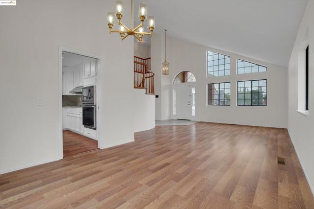Unfurnished dining area with high vaulted ceiling, a chandelier, and light wood finished floors