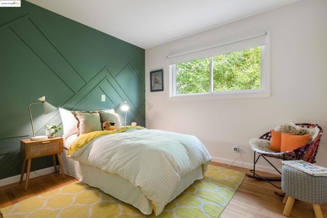 Bedroom featuring wood finished floors and an accent wall