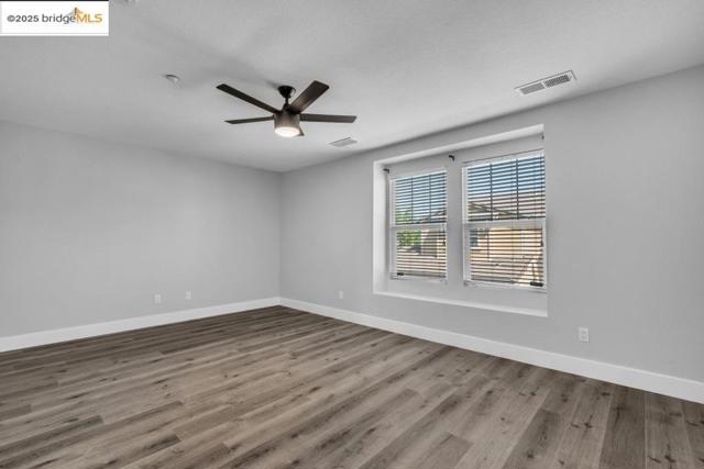 Spare room with wood finished floors and a ceiling fan