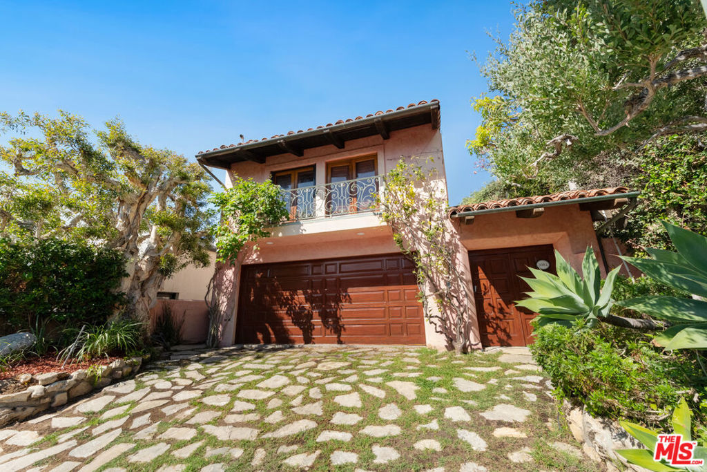 Nestled in the prestigious and private Malibu Colony, this home offers a blend of luxurious coastal living with modern comforts. Upon entering the gated driveway, which provides secure parking for two vehicles, you are greeted by a meticulously landscaped front yard equipped with a sprinkler system. The property boasts a two-car garage, complete with a washer and dryer, water heater, and direct entry to the home. Above the garage lies a charming guest house, accessible via a set of steps that lead to a covered front door. The guest house offers a cozy yet spacious studio with beamed ceilings, tile floors, and French doors that open to a balcony, perfect for use as a living or sleeping area. The adjacent bathroom features a stone countertop and a shower stall, while the compact kitchen is equipped with stone counters, French windows, a 4-burner range, and essential appliances like a fridge and freezer. From the guest house, a beautifully landscaped walkway guides you through the courtyarda true outdoor oasis. This private space, framed by lush trees, includes a built-in outdoor living area with a couch and wet bar complete with bar seating, ideal for entertaining or quiet relaxation. A covered walkway leads from the courtyard to the main house, where you're welcomed by a covered front door and a charming foyer with wood-beamed ceilings and hardwood floors. Inside the main house, the living room exudes warmth and elegance, featuring a cozy fireplace framed by custom built-ins and multiple sets of French doors that flood the space with natural light. These doors open to the backyard, which boasts a stunning pool, jacuzzi, and stone floors, all surrounded by beautifully landscaped grounds and a privacy fence. The living room flows seamlessly into the gourmet kitchen, a chef's dream equipped with stone counters, custom wood cabinetry, a 4-burner range, a 2-burner electric stovetop, double Gaggenau ovens, a Sub-Zero fridge, a dishwasher, and a microwave. Just down the hall, you'll find a butler's pantry with additional freezer space, stone countertops, and built-ins for added convenience. The home features multiple bedrooms, each thoughtfully designed for comfort and privacy. The first-floor bedroom includes wood floors, recessed lighting, and French doors that open to the courtyard, offering a serene escape. Upstairs, the second bedroom is carpeted, with wood-beamed ceilings, built-in storage, and a private balcony with views of the courtyard. The en-suite bathroom is beautifully appointed with stone counters, a shower over tub, and a vanity sink. The master suite, located on the top floor, is a true sanctuary with plush carpet, high wood-beamed ceilings, and breathtaking panoramic views of the ocean and coastline, including the iconic Malibu Pier. The master suite also features a fireplace and French doors leading to a private balcony with views of both the ocean and the pool. The luxurious master bath is equally impressive, featuring wood floors, stone countertops, double sinks, a vanity, and a built-in tub with ocean views. The en-suite bathroom also includes a separate water closet and shower stall, as well as a spacious walk-in closet. This Malibu Colony residence offers a harmonious blend of indoor and outdoor living, with thoughtful design details and luxurious amenities throughout. Whether enjoying the privacy of the guest house, entertaining in the outdoor courtyard, or relaxing in the master suite with ocean views, this property is a true coastal paradise.