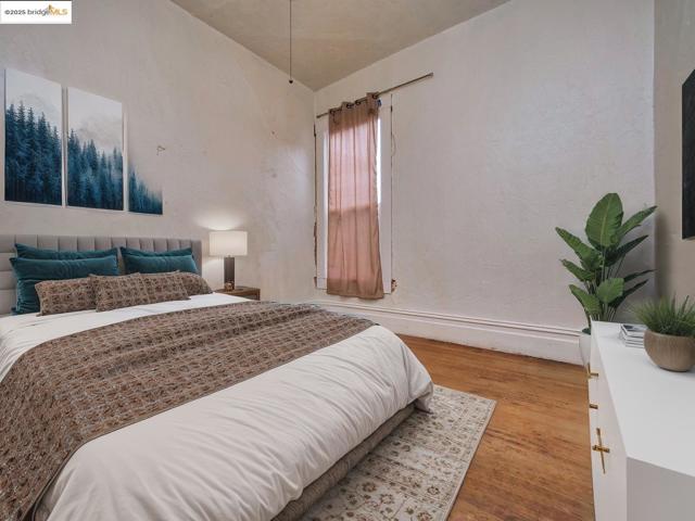Bedroom with light wood-style flooring and a textured wall. Virtually staged.