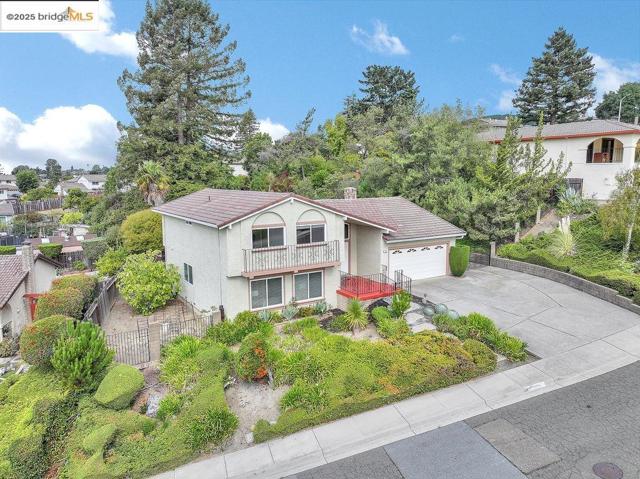 View of front of house with a balcony, driveway, a tile roof, stucco siding, and an attached garage
