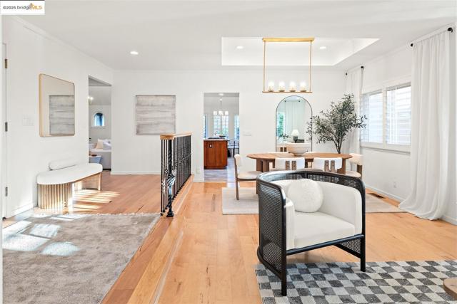 Living area featuring light wood-style floors, healthy amount of natural light, recessed lighting, a chandelier, and a tray ceiling