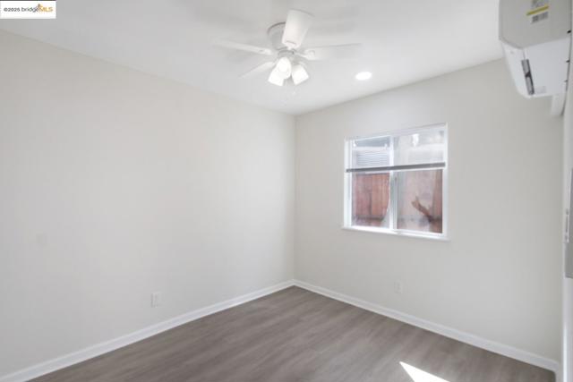 Bedroom featuring dark wood-style flooring, a ceiling fan, a wall unit HVAC, and recessed lighting