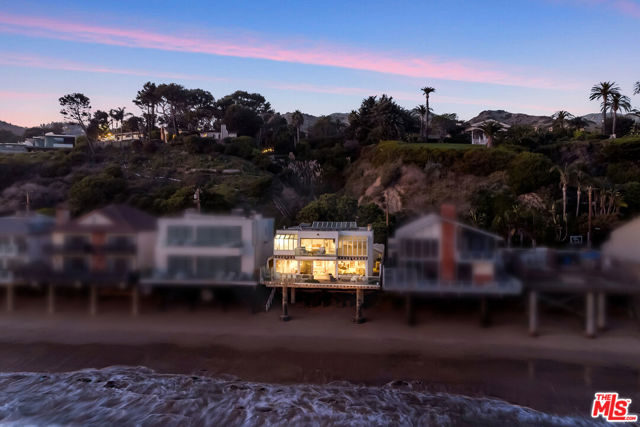 Situated in the center of Malibu's coveted shoreline, this beachfront masterpiece is a testament to stylish coastal living. Designed by renowned architect Ron Goldman, this residence combines impeccable craftsmanship with breathtaking ocean vistas to create the ultimate coastal escape. Depicted as Robert DeNiro's house in the movie Heat, this home is located on a private and guard-gated street - allowing you to relax and enjoy your seaside sanctuary with peace of mind. The unique and contemporary design seamlessly blends with its beachfront surroundings. Enter the home through a gated courtyard to the glass entrance which allows for a peek at what lies within - an open and spacious layout that is perfect for showcasing art.  The ground level features a large oceanfront deck for dining and entertaining, open living and family rooms with fireplaces, dining area and open kitchen along with a bedroom and bath. The remaining bedrooms are on the upper level and are flooded with sunlight from glass ceilings and sliding glass doors designed to let in the ocean influence. The master includes a living/sitting area, large deck, spectacular views and oceanfront bathtub for the ultimate beachfront experience. This home is a rare gem that provides the best of coastal living in one of Southern California's most prestigious communities. Whether you seek a tranquil escape, an art lover's paradise, or a place to entertain family and friends, this Malibu masterpiece offers it all.