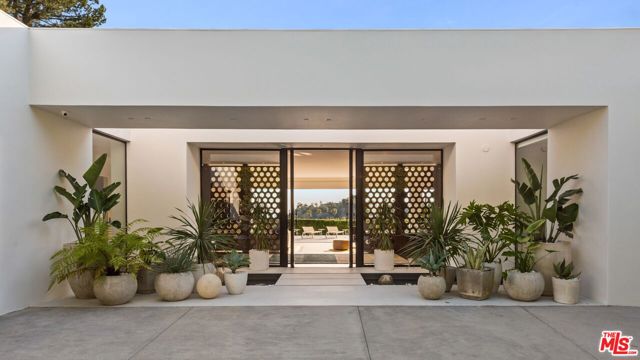 This beautiful modern estate has been completely rebuilt in every detail, chic and sophisticated. Situated on an exceptionally large 25,000 SF lot with expansive views from Beverly Hills to the ocean. Quintessential Hollywood style and a grand entryway lead to a living room w/floor-to-ceiling sliders that open to a Slim Aarons picturesque backyard & pool. A master suite fit for the most discerning buyers: Featuring a luxurious bathroom w/his and hers sinks & free standing dark green lucite tub, a walk-in-closet, bar and private lounge. Infinity pool with spa and impressive outdoor fire pit area perfect for indoor/outdoor entertaining. Many dreamed of a lifestyle as sweet as this. You were born in the right time & earned it. Don't miss out on one of the most stylistic, effortlessly beautiful homes in Trousdale.