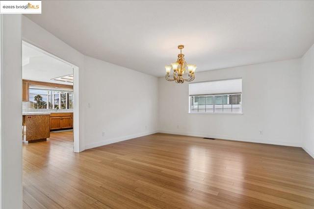 Spare room featuring a chandelier and light wood-style flooring