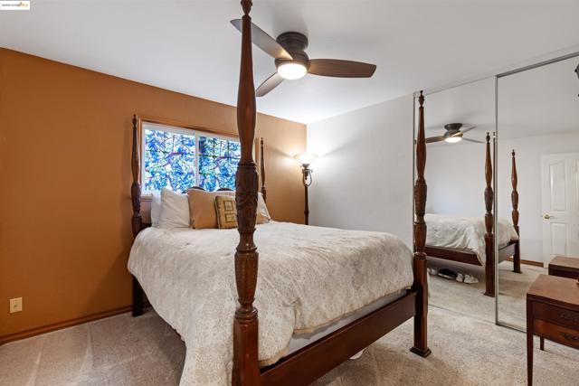 Bedroom with a closet, light colored carpet, and ceiling fan