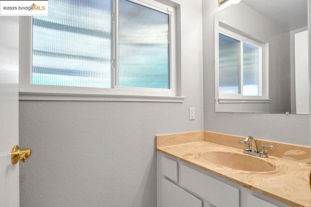 Bathroom with a textured wall and vanity